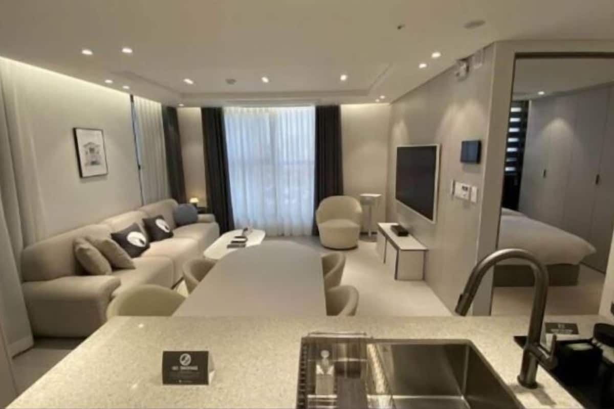 Een moderne hotelkamer met een bank, een eettafel, een televisie en een geïntegreerde keukenhoek.
