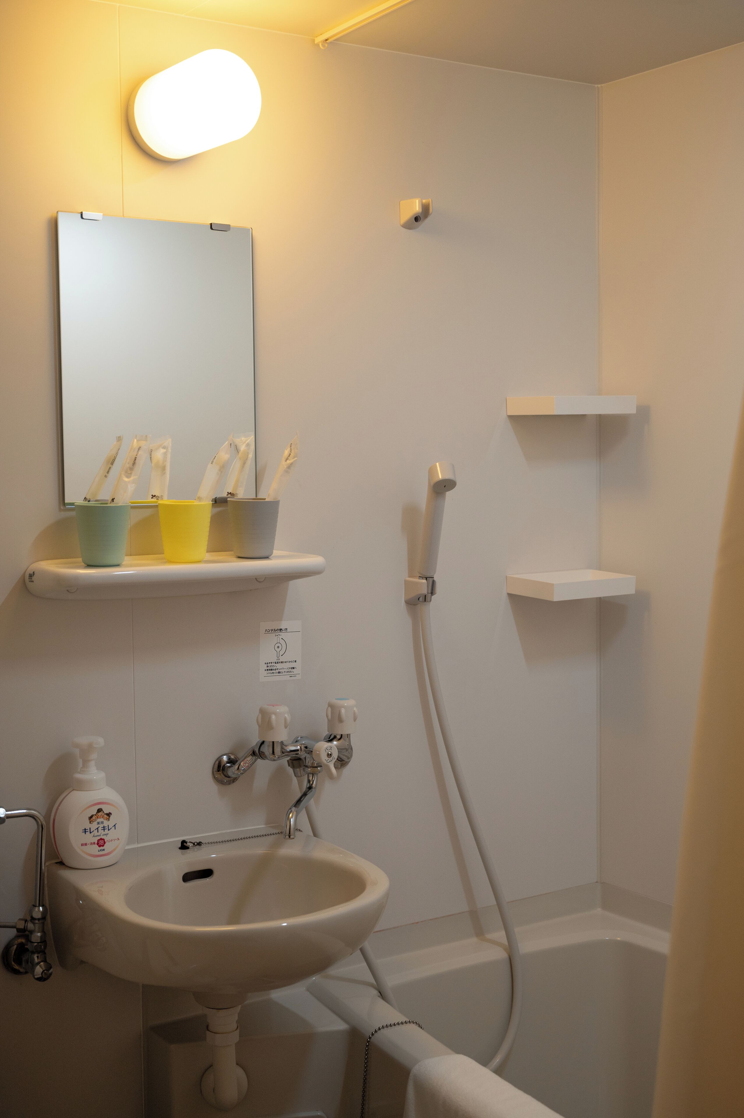 A bathroom with a sink, mirror, and shower.