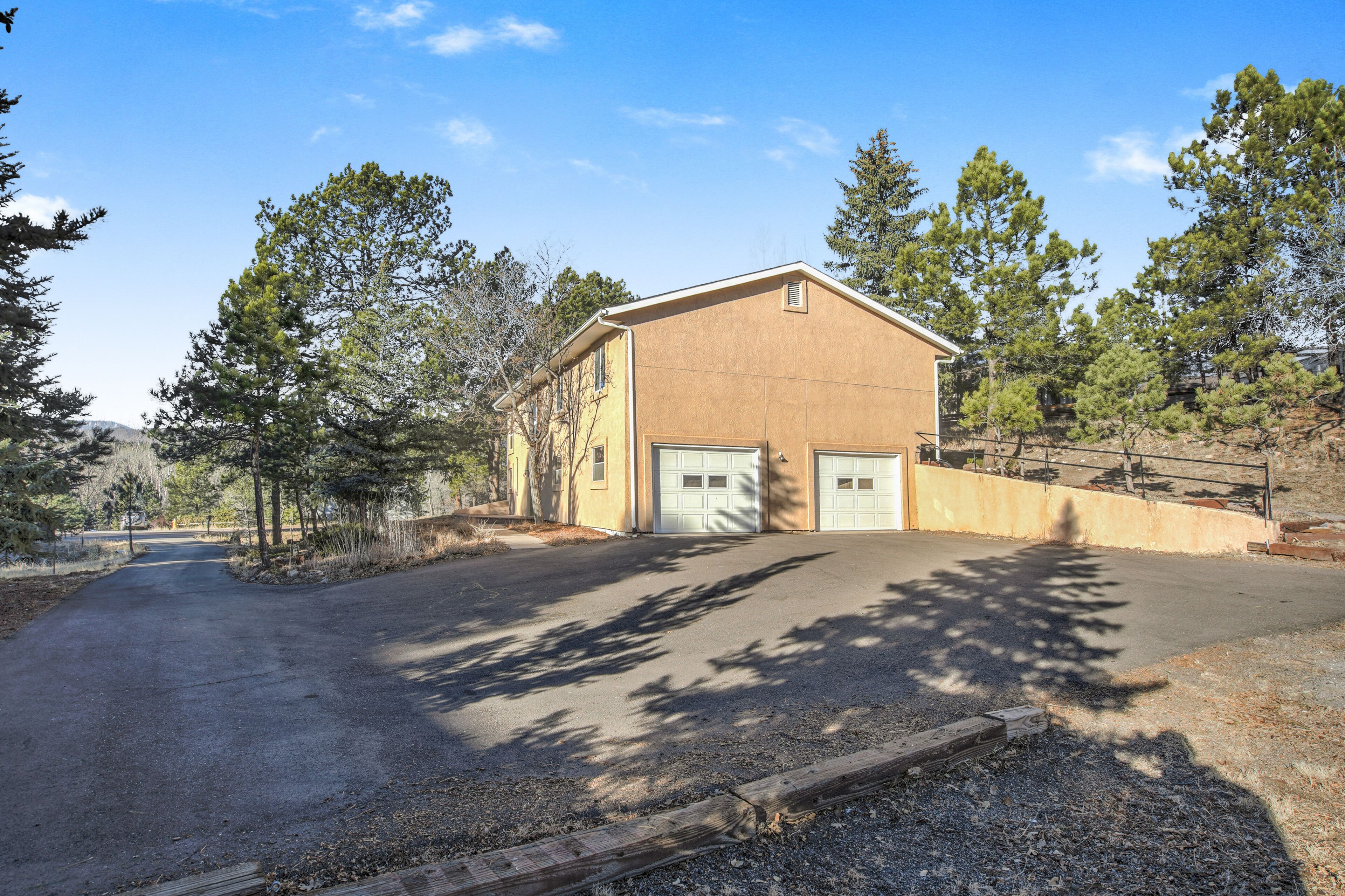 A single-story building with a garage, surrounded by trees and a clear sky.