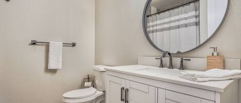 A bathroom with a toilet, sink, mirror, and towel rack.