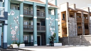 Un edificio de varios pisos con balcones, un mural con motivos florales y el número 127 en la fachada.