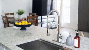 A kitchen with a granite countertop, stainless steel sink, and a bowl of lemons. - 202, Ocean Side, Patio, Laundry, Desk (South Padre Island)
