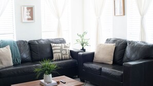 A modern living room with a black leather sofa, a wooden coffee table, and a small side table. - 302, Ocean Side, Patio, Laundry, Desk (South Padre Island)