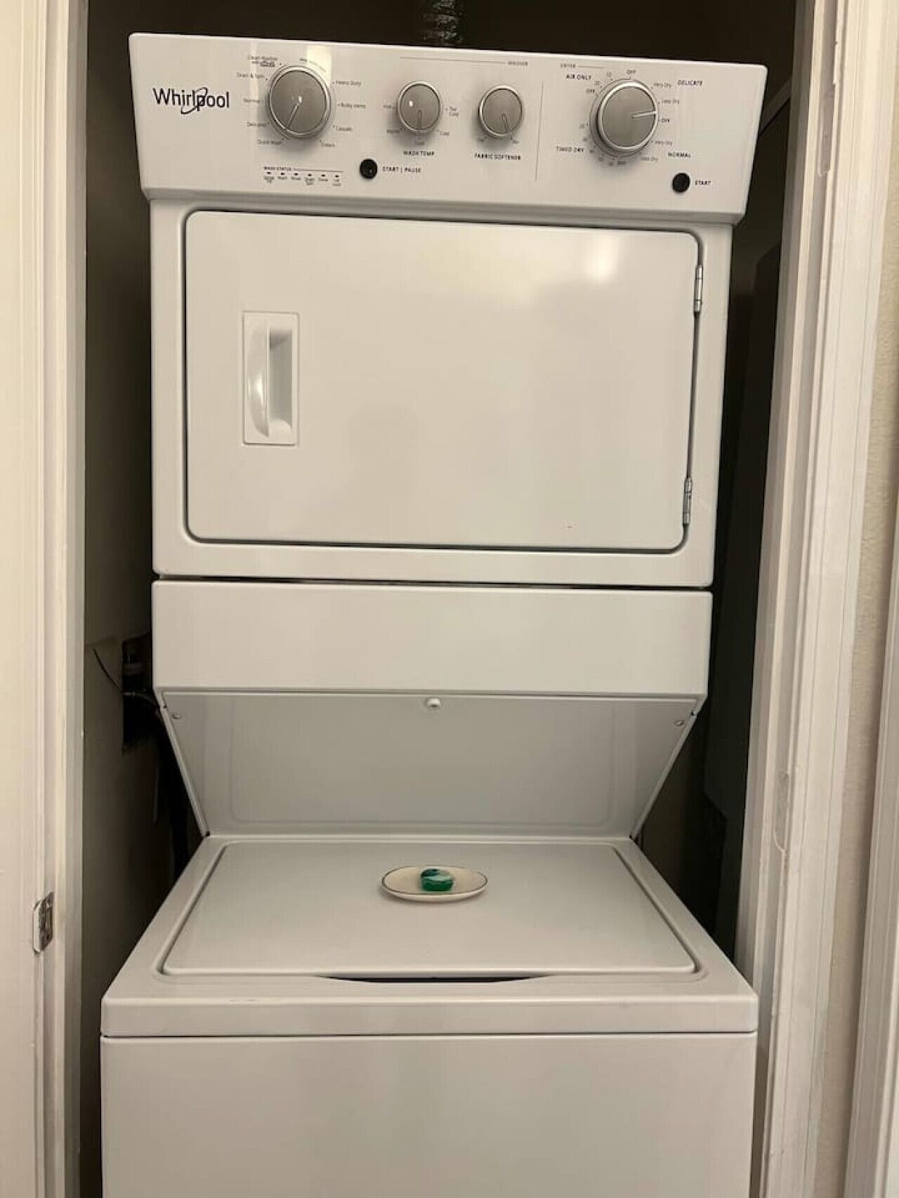 Lavadora y secadora Whirlpool apiladas, con perillas de control y botón de inicio/pausa.