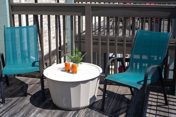 A round outdoor table with two chairs, a small potted plant, and two cans of beverage. - 302, Ocean Side, Patio, Laundry, Desk (South Padre Island)