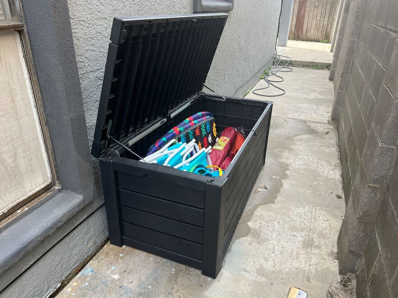 A black storage box with its lid open, containing colorful items.