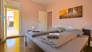 A bedroom with a bed, a nightstand, a painting, and a door leading to a balcony. - Cozy apartment in Buje with WiFi (Buje)