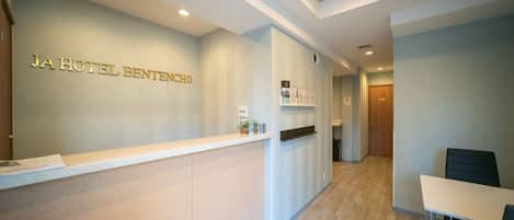 A reception area with a reception desk, a wall-mounted display, and a seating area with a table and chairs.