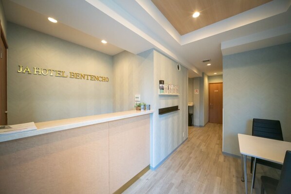 A reception area with a reception desk, a wall-mounted display, and a seating area with a table and chairs.
