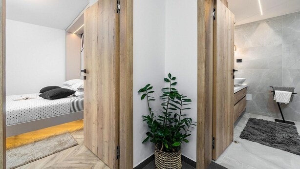 Un dormitorio moderno con cama, mesita de noche y una planta en maceta.