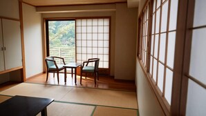 Una habitación tradicional japonesa con suelo de tatami, una mesa baja y dos sillas.