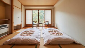 Una habitación tradicional japonesa con suelo de tatami, una puerta corredera shoji y vistas a un jardín.