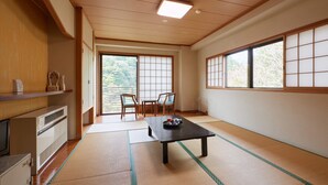 Una habitación japonesa tradicional con suelo de tatami, una mesa baja con bandeja y puertas correderas que dan a un balcón.