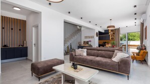 A modern living room with a brown sofa, a glass coffee table, and a patterned rug.