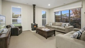 A modern living room with a fireplace, a sofa, a coffee table, and a TV.