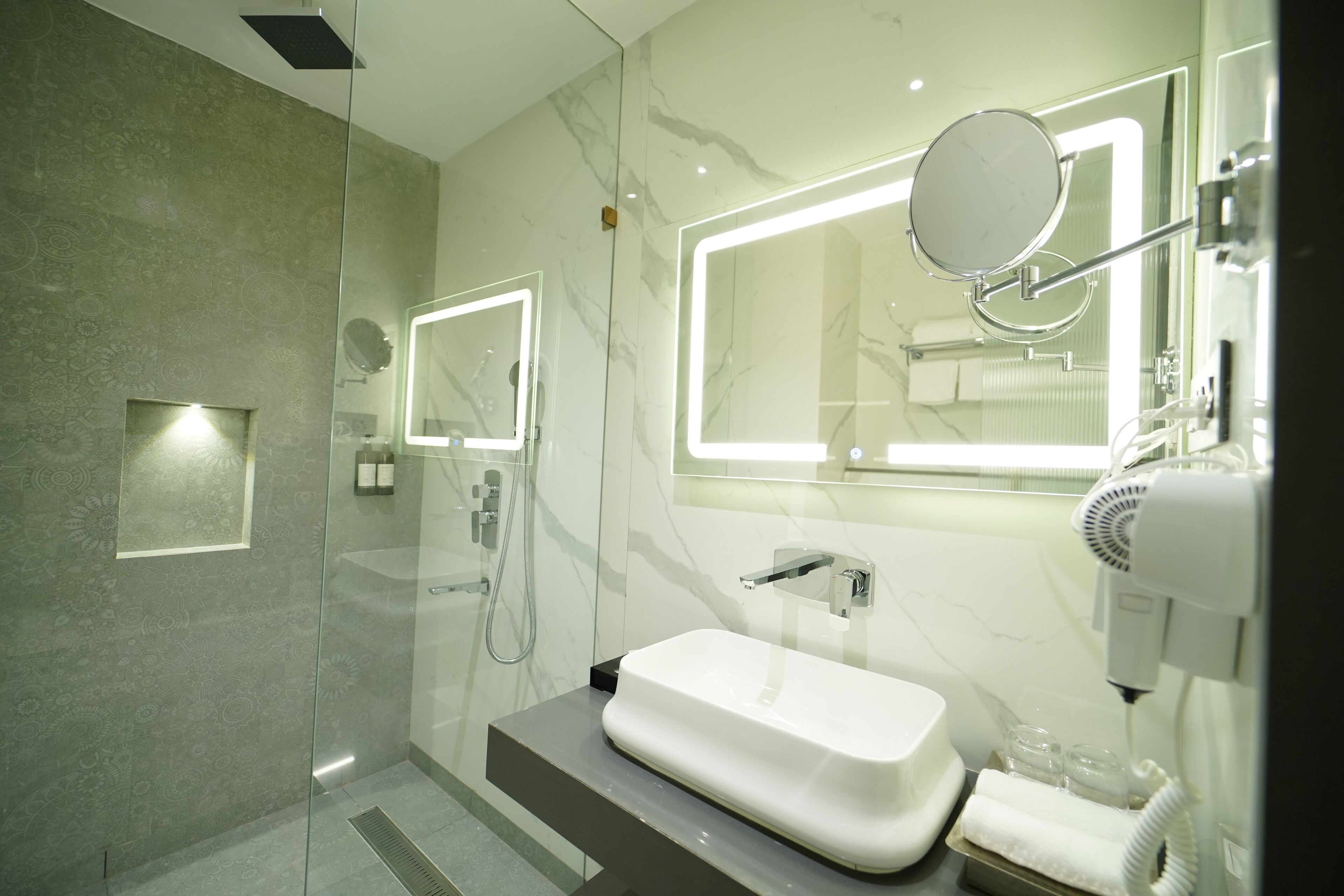 A modern bathroom with a glass-enclosed shower, a white sink, and a hairdryer.