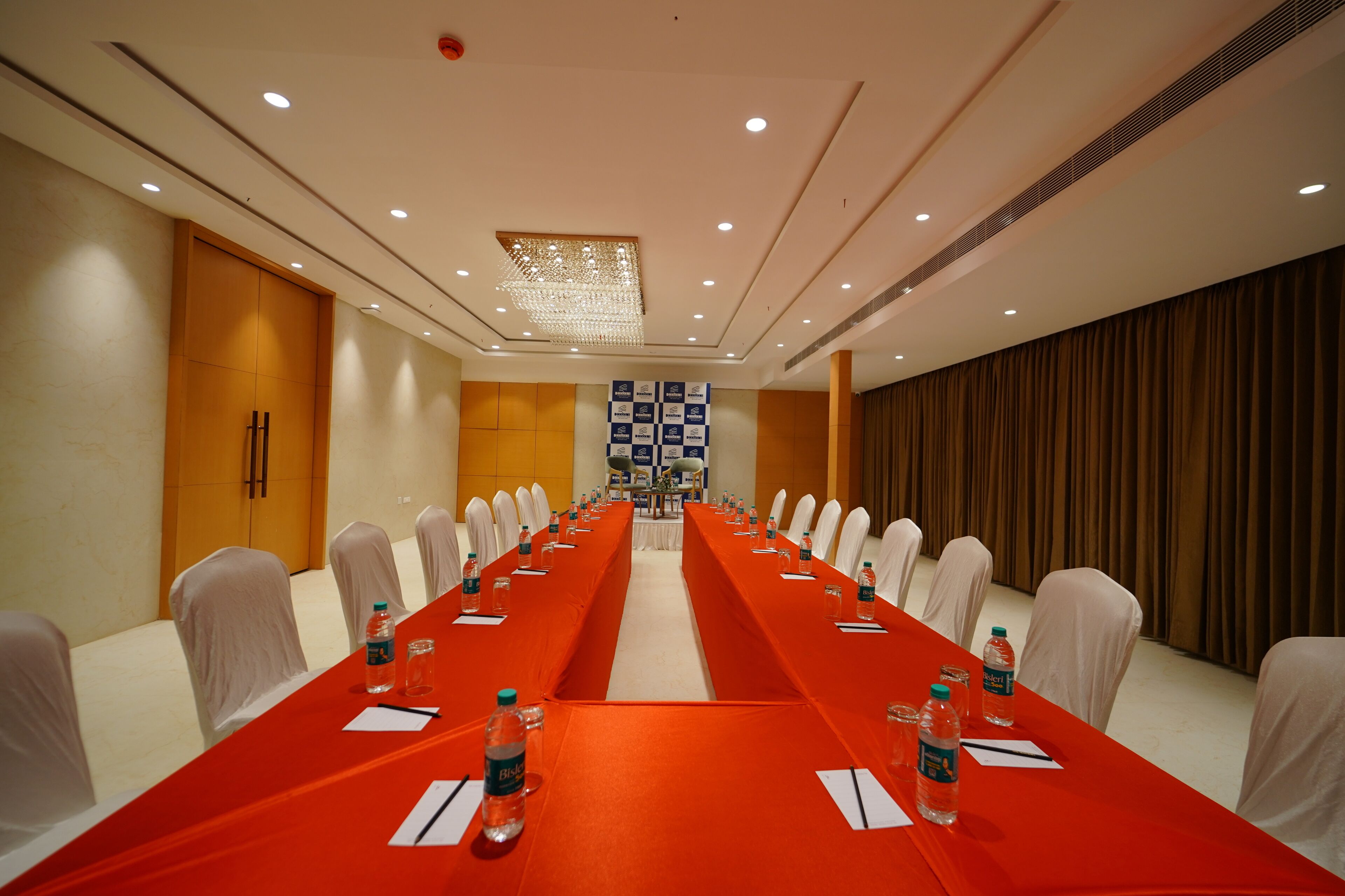 Un salón de conferencias con una larga mesa, sillas y botellas de agua.