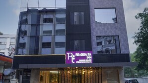 Ett modernt hotell med en reflekterande glasfasad, ett tydligt skylt med texten ”RE:GEN:TA INN” och en väl upplyst entré.