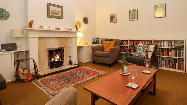 Een gezellige woonkamer met een open haard, een boekenkast, een salontafel en een comfortabele zithoek.