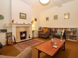 A cozy living room with a fireplace, a bookshelf, a coffee table, and a comfortable seating area. - Cedars (Penrith)