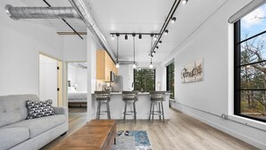 A modern living space with a sofa, coffee table, and kitchen area with bar stools.