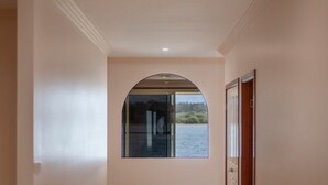 A hallway with a large arched window, a door, and a ceiling with recessed lighting.