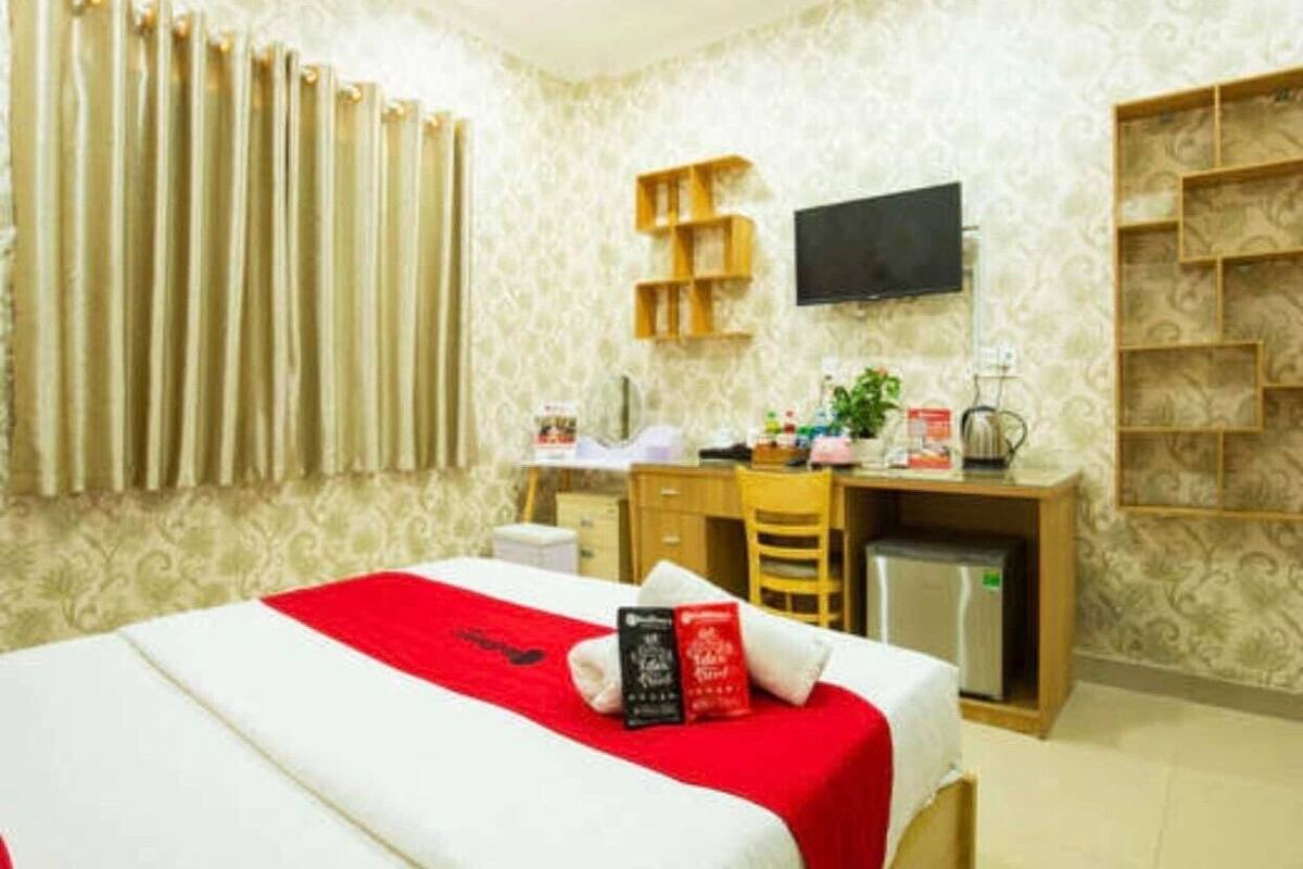 A hotel room with a bed, a desk, a chair, a television, and a small refrigerator.