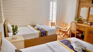 Habitación de hotel con dos camas, un escritorio pequeño, una silla y una planta en maceta.