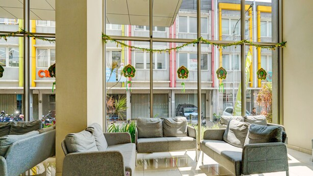 A modern waiting area with comfortable seating and large windows offering views of the cityscape. - OYO Life 92548 M-square Apartment By Lins Pro (Bandung)