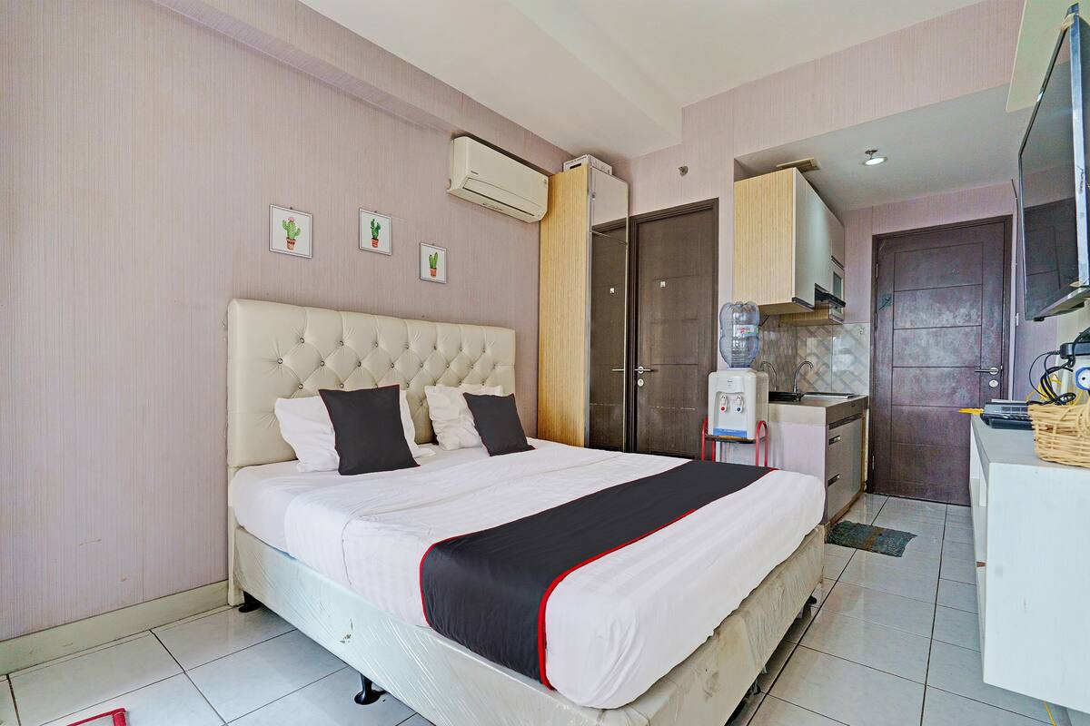 Une chambre d’hôtel dotée d’un grand lit, d’un distributeur d’eau, d’une kitchenette et d’un téléviseur.
