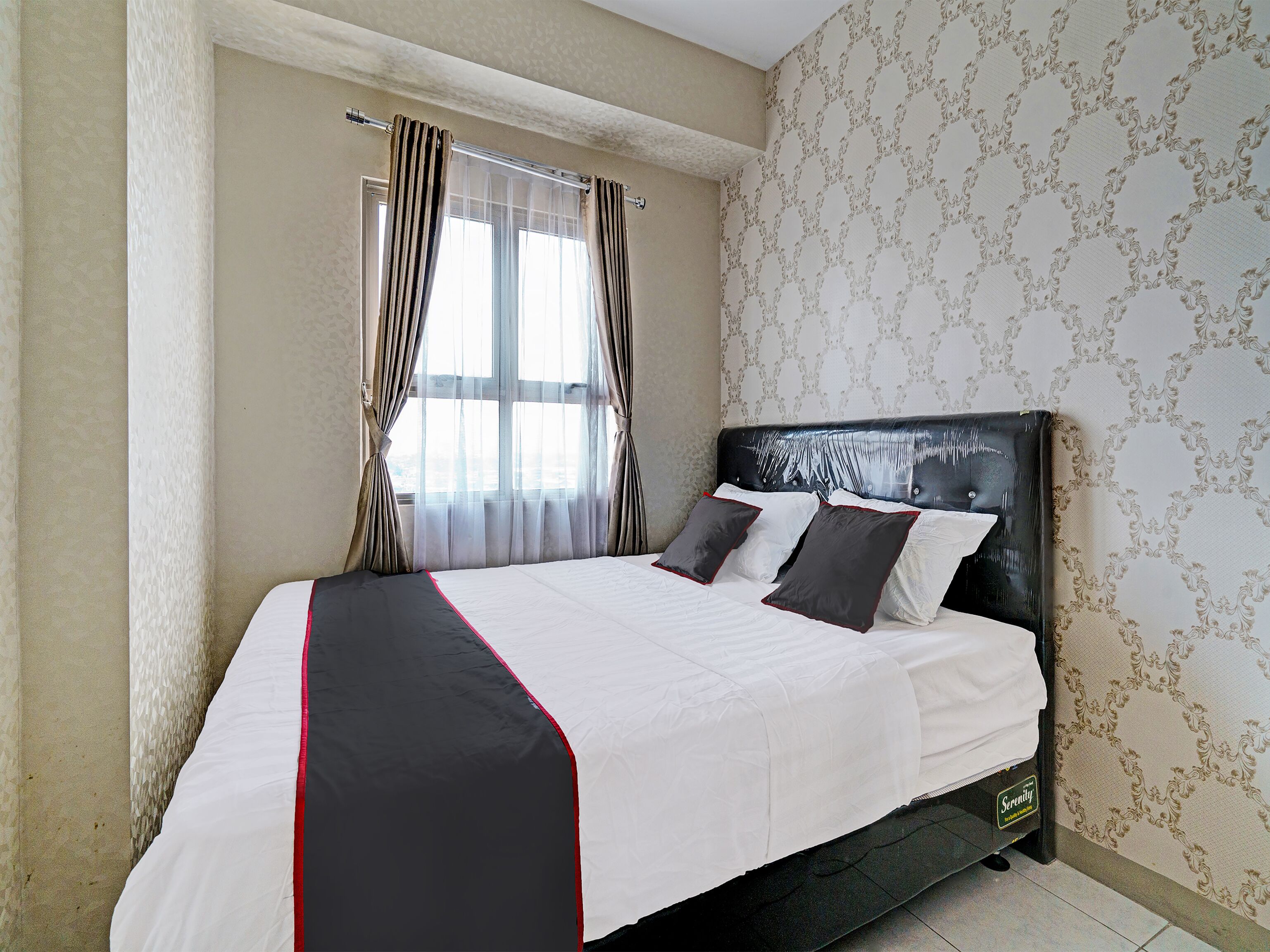 A neatly made bed with a black and white bedspread, a headboard, and two pillows.
