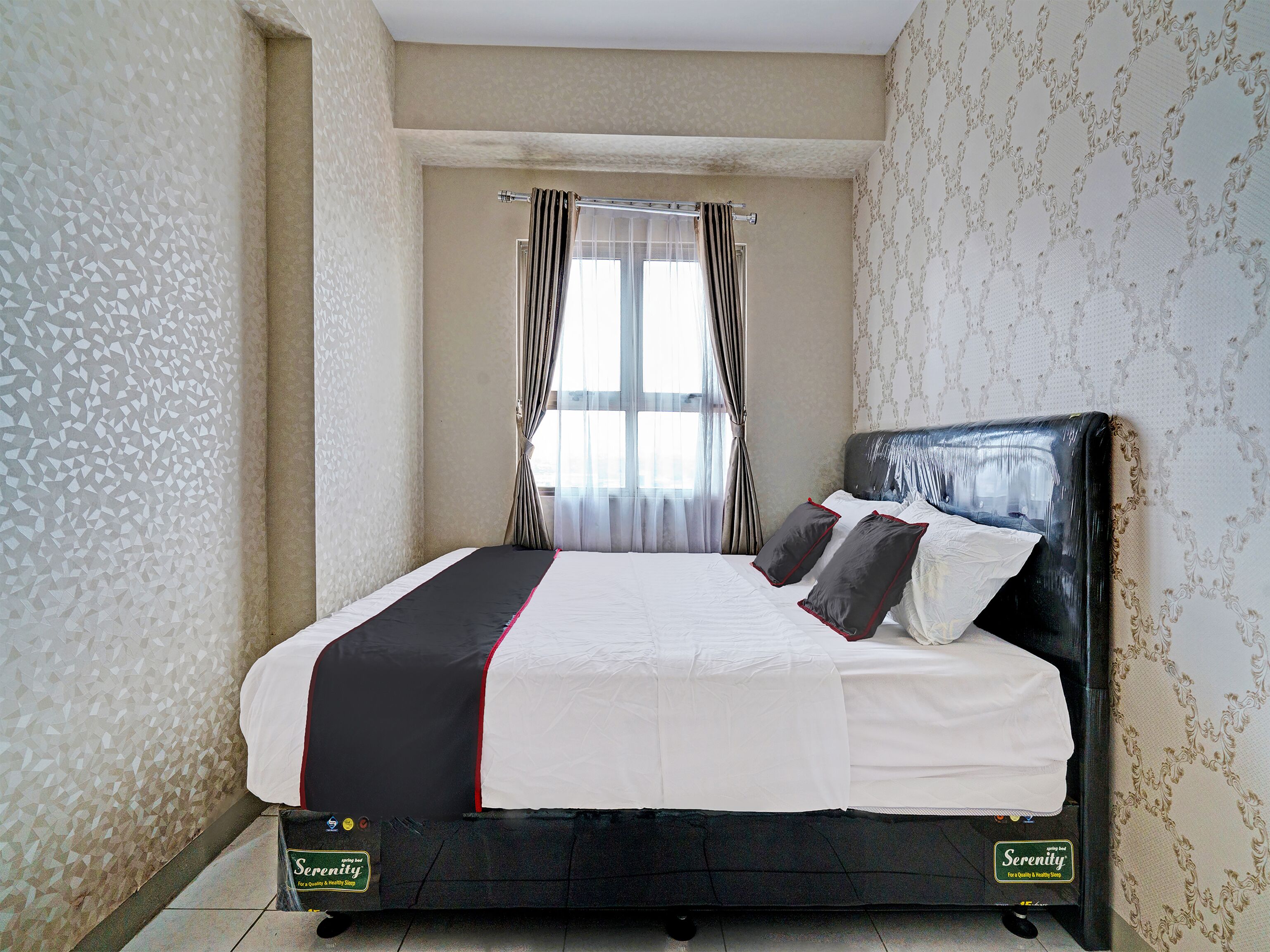 A neatly made bed with a black and white bedspread, a headboard, and two pillows.