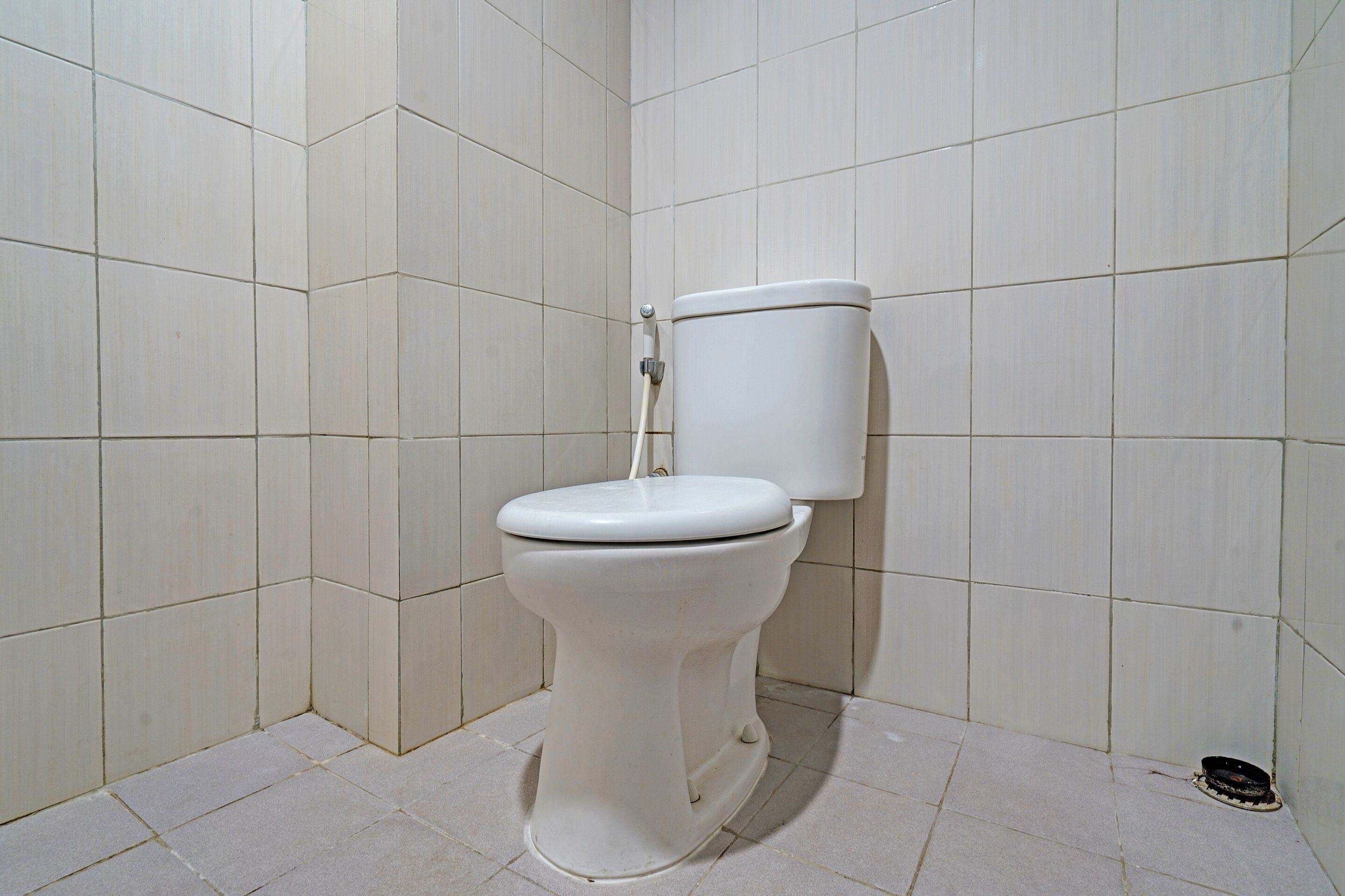 Un inodoro blanco en un baño con paredes y suelo de baldosas.