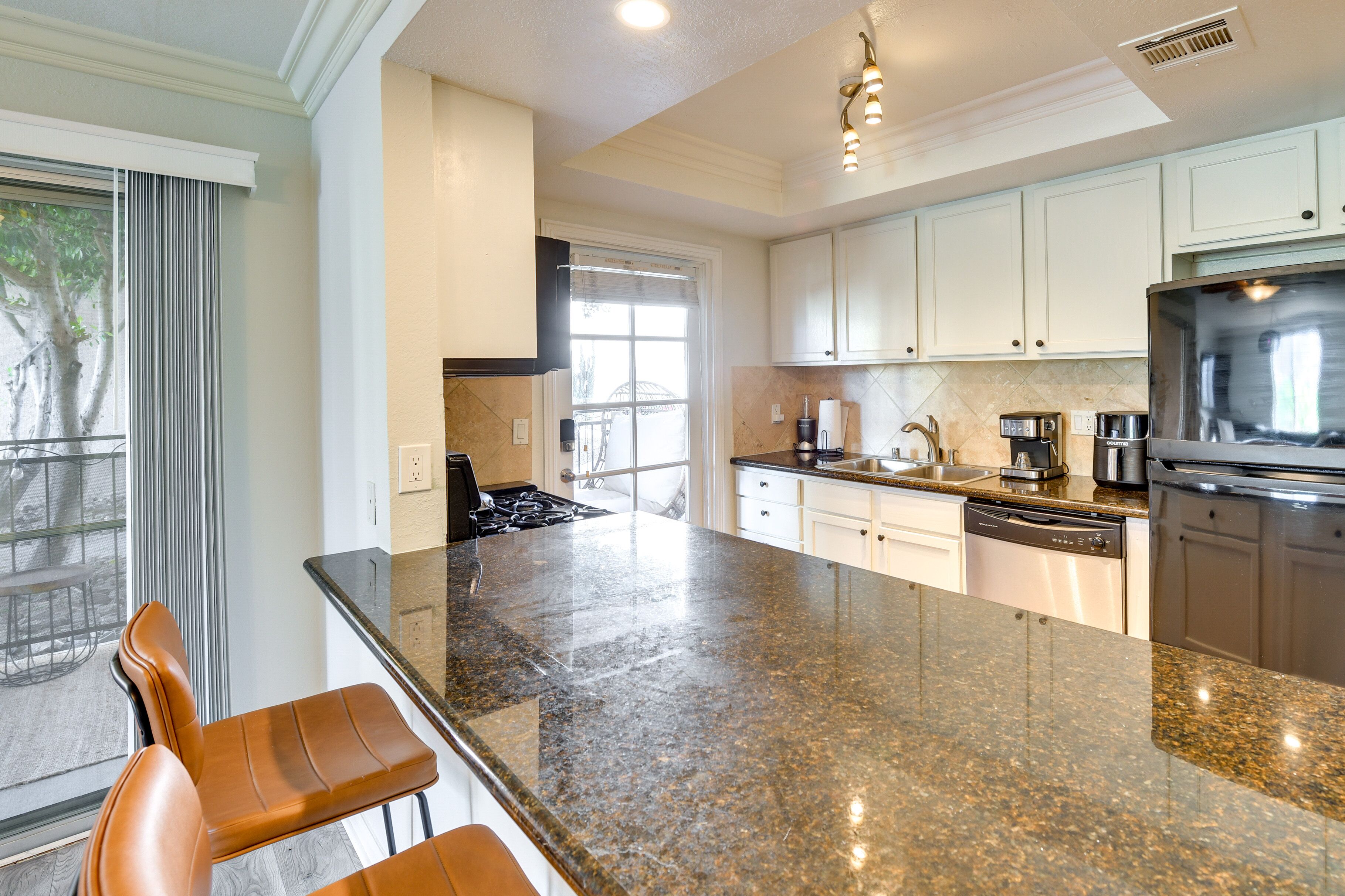 A modern kitchen with granite countertops, stainless steel appliances, and white cabinetry.