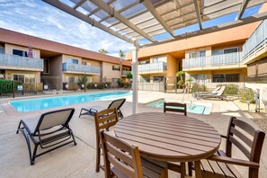 Un espace aménagé au bord de la piscine, avec un patio couvert, des chaises longues et une table.