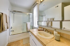 Enjoy a refreshing shower or soak in the standalone bathtub in this bathroom, featuring a glass-enclosed shower and vanity with sink and mirror.