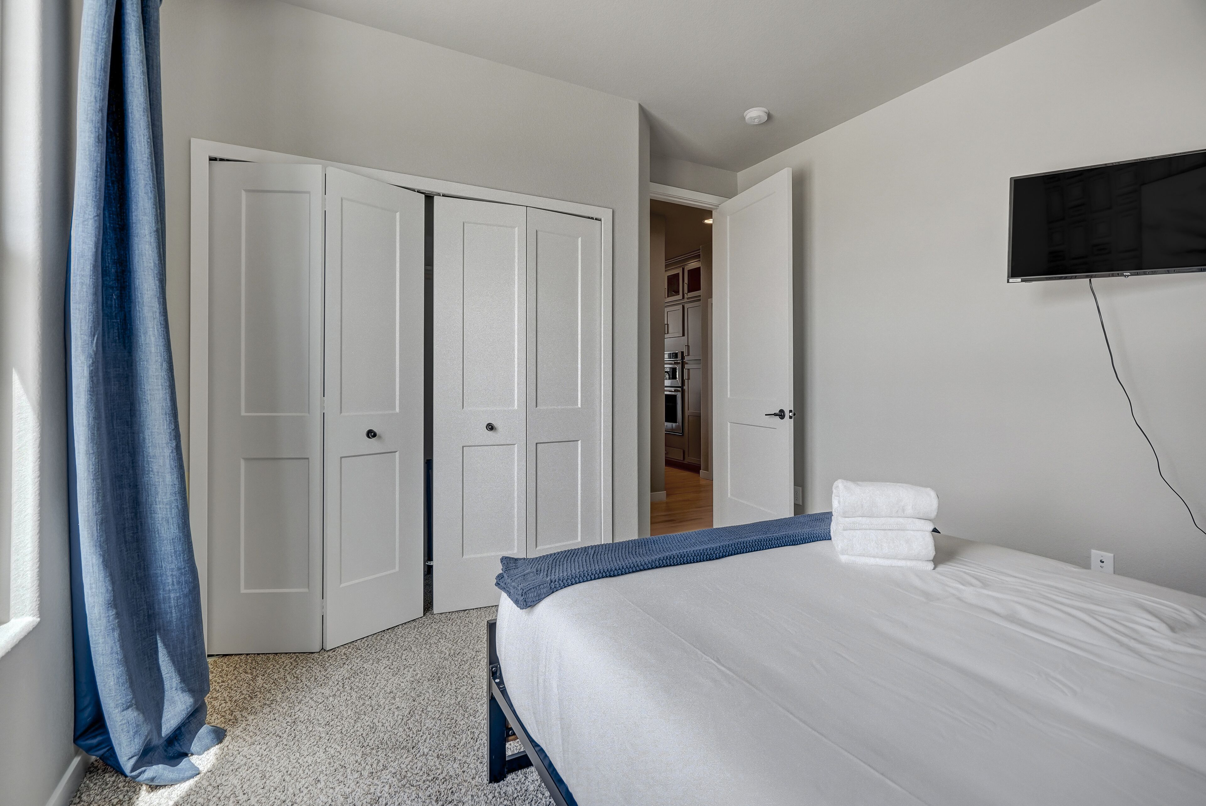 Une chambre d’hôtel avec un lit, un téléviseur fixé au mur et une armoire avec des portes coulissantes.