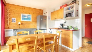 Une cuisine de taille réduite, avec des meubles de rangement en bois, un réfrigérateur et un four à micro-ondes.
