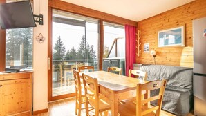 L’intérieur chaleureux d’un chalet avec une table à manger en bois, des chaises, un canapé et un réfrigérateur.