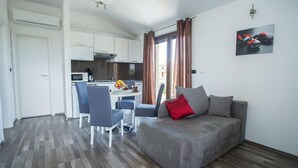 Un espace de vie compact comprenant un coin cuisine, un coin repas et un espace détente avec un canapé et des fauteuils.