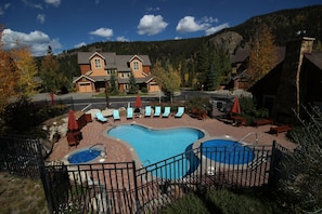 A resort with a swimming pool, lounge chairs, and a mountain backdrop. - Settlers Creek 6528 (Keystone)