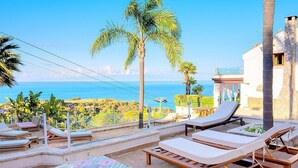 A terrace with lounge chairs and a view of the sea.