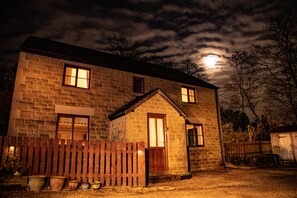 A stone house with a wooden door and windows, surrounded by a wooden fence and potted plants. - Sunset View (Matlock)