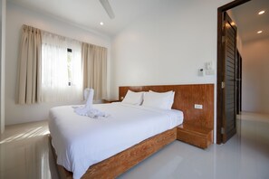 A neatly made bed with white linens, a wooden headboard, and a white towel on the bed. - Paradise Found (Rawai)