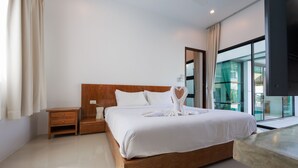 A modern hotel room with a wooden bed, a nightstand, and a large window offering a view of the outdoors. - Paradise Found (Rawai)