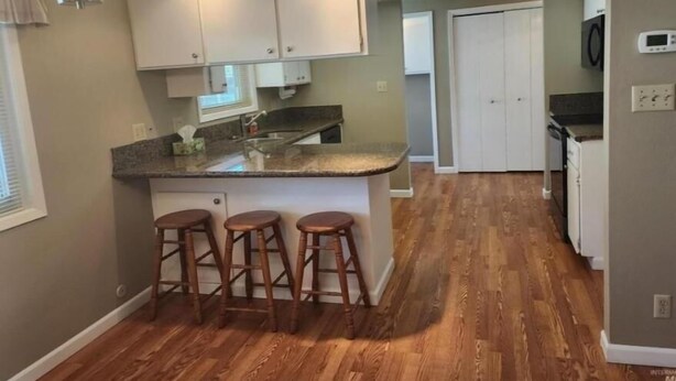 A kitchen with a central island, bar stools, and a microwave. - Cozy country house near major stores, markets. Ideal for your perfect vacation. (Nampa)