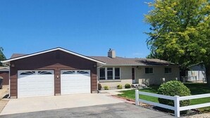 A single-story house with a garage and a small front porch. - Cozy country house near major stores, markets. Ideal for your perfect vacation. (Nampa)