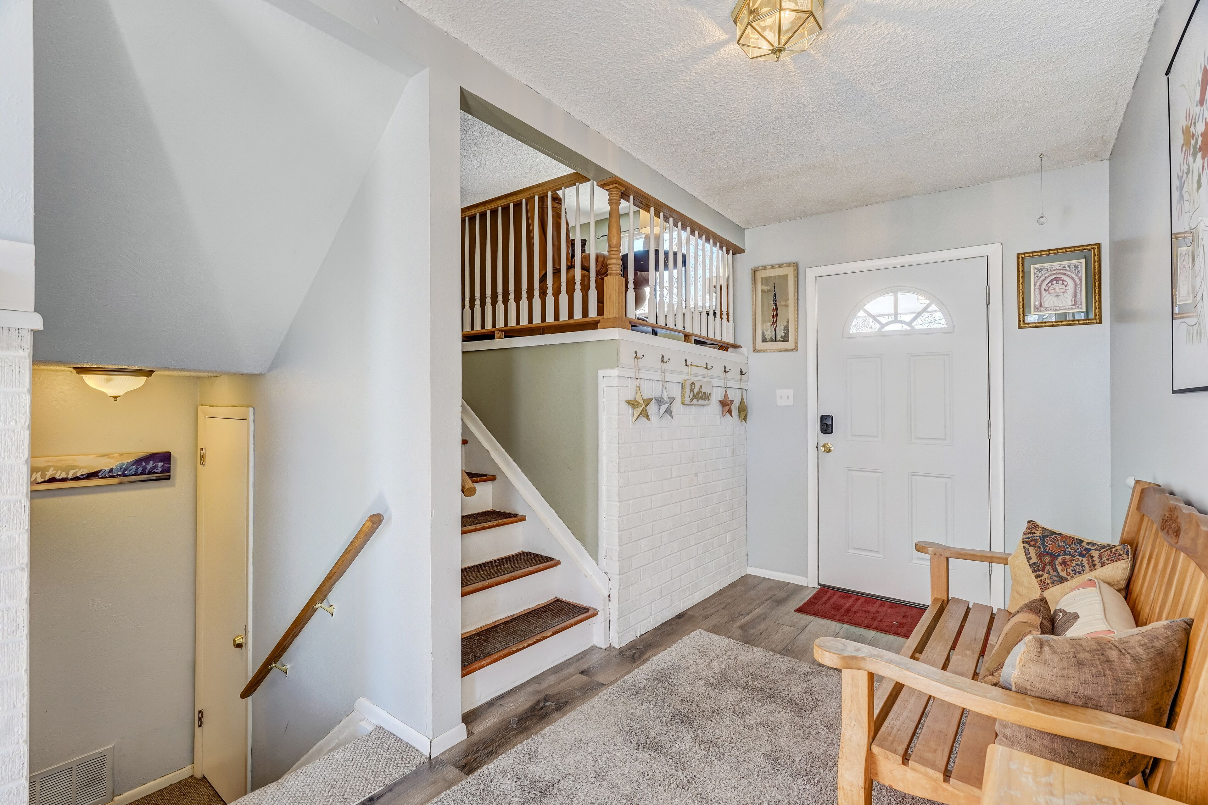 A staircase with wooden railings, a white door, and a bench with pillows.