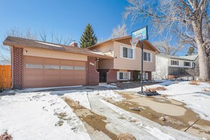 A two-story house with a garage, a basketball hoop, and a driveway partially covered in snow. - Always Somerset (Colorado Springs)