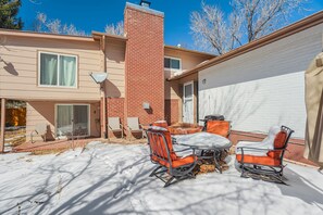 A two-story house with a brick chimney, a patio with outdoor furniture, and a garage. - Always Somerset (Colorado Springs)